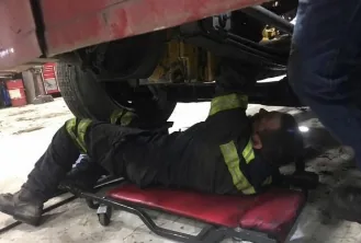 Mechanic performing repairs underneath a semi-truck